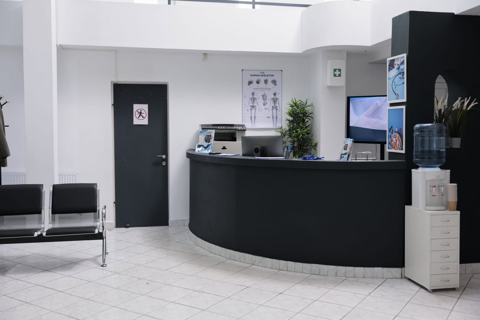 Nobody in waiting room with front desk reception and wall screen tv with promotional offer